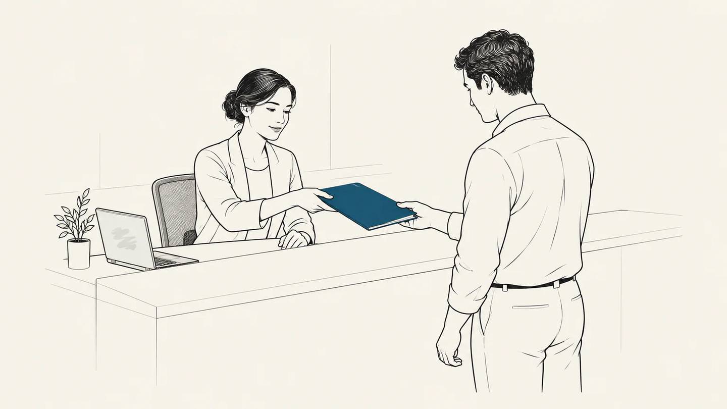 An employee hands a customer a folder while the laptop stays to one side.