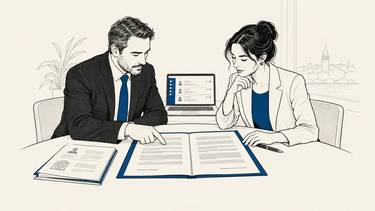 Customer and supplier review a contract beside a laptop displaying customer records.