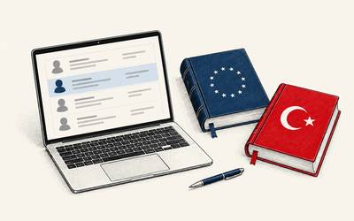 A laptop displaying customer records sits beside a navy law book with EU stars and a red law book with a white Turkish crescent and star.